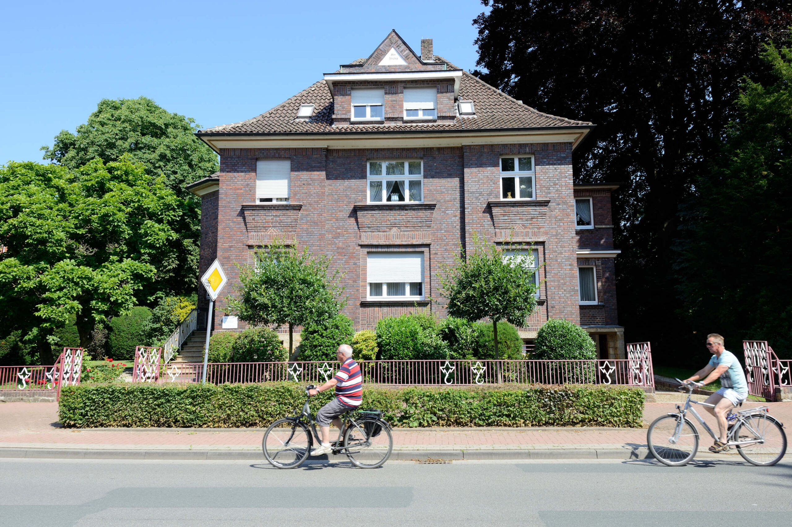 Straßenszene mit Radfahrern vor einem Backsteinhaus in Fürstenau.