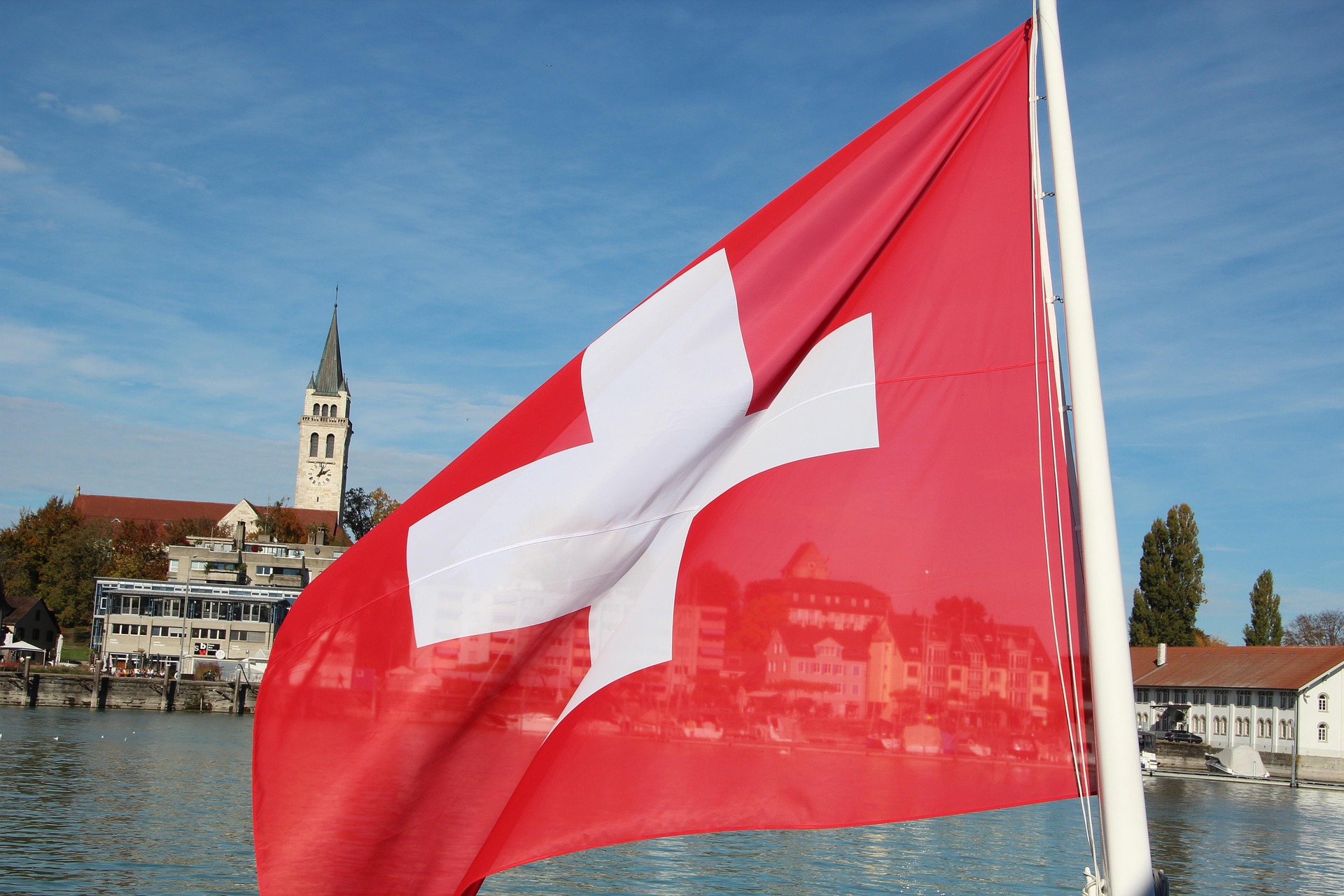 Schweizer Flagge mit Stadtpanorama im Hintergrund – Schweiz