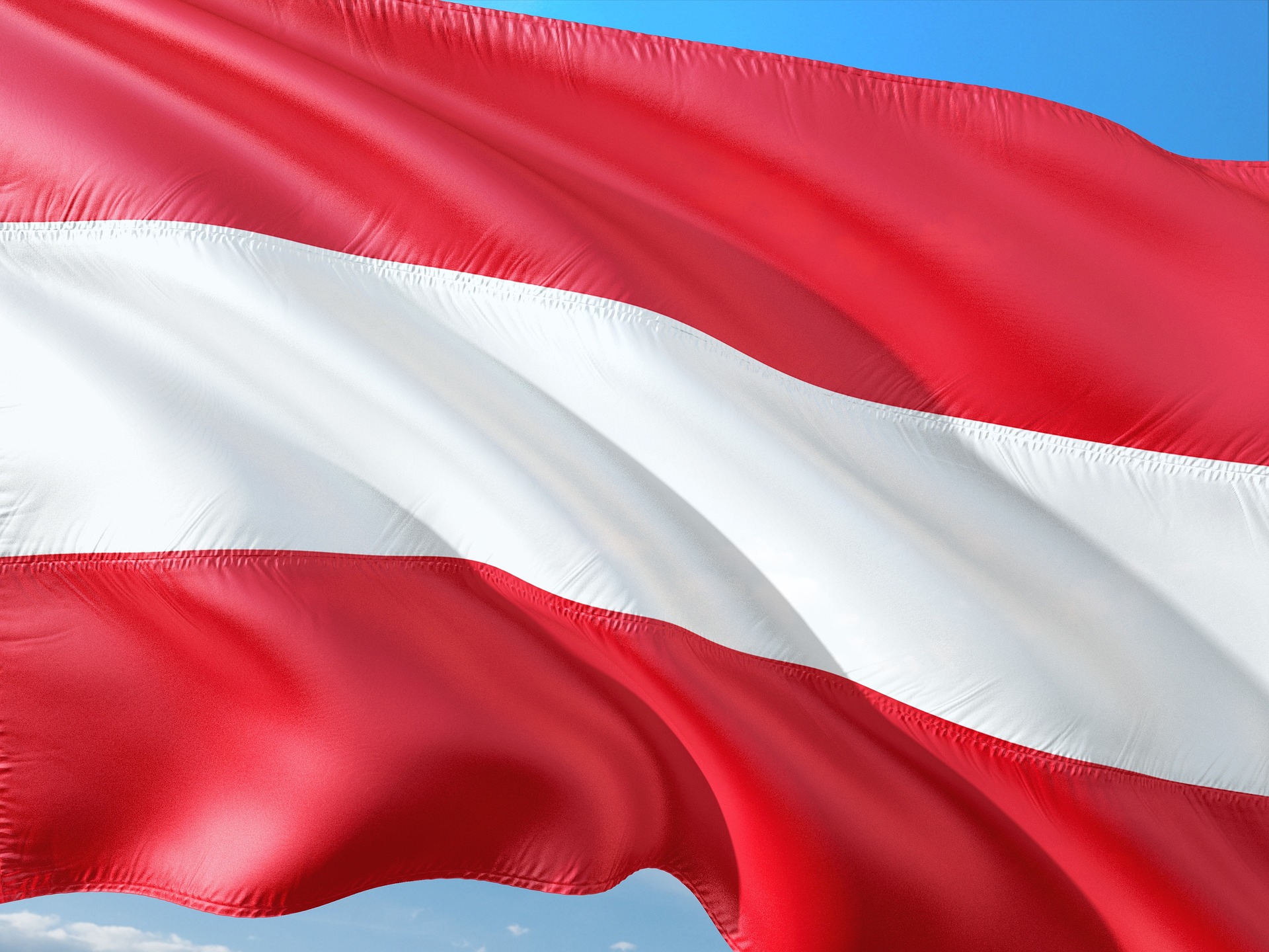 Österreich-Flagge – Wehende rot-weiß-rote Fahne vor blauem Himmel, Österreich
