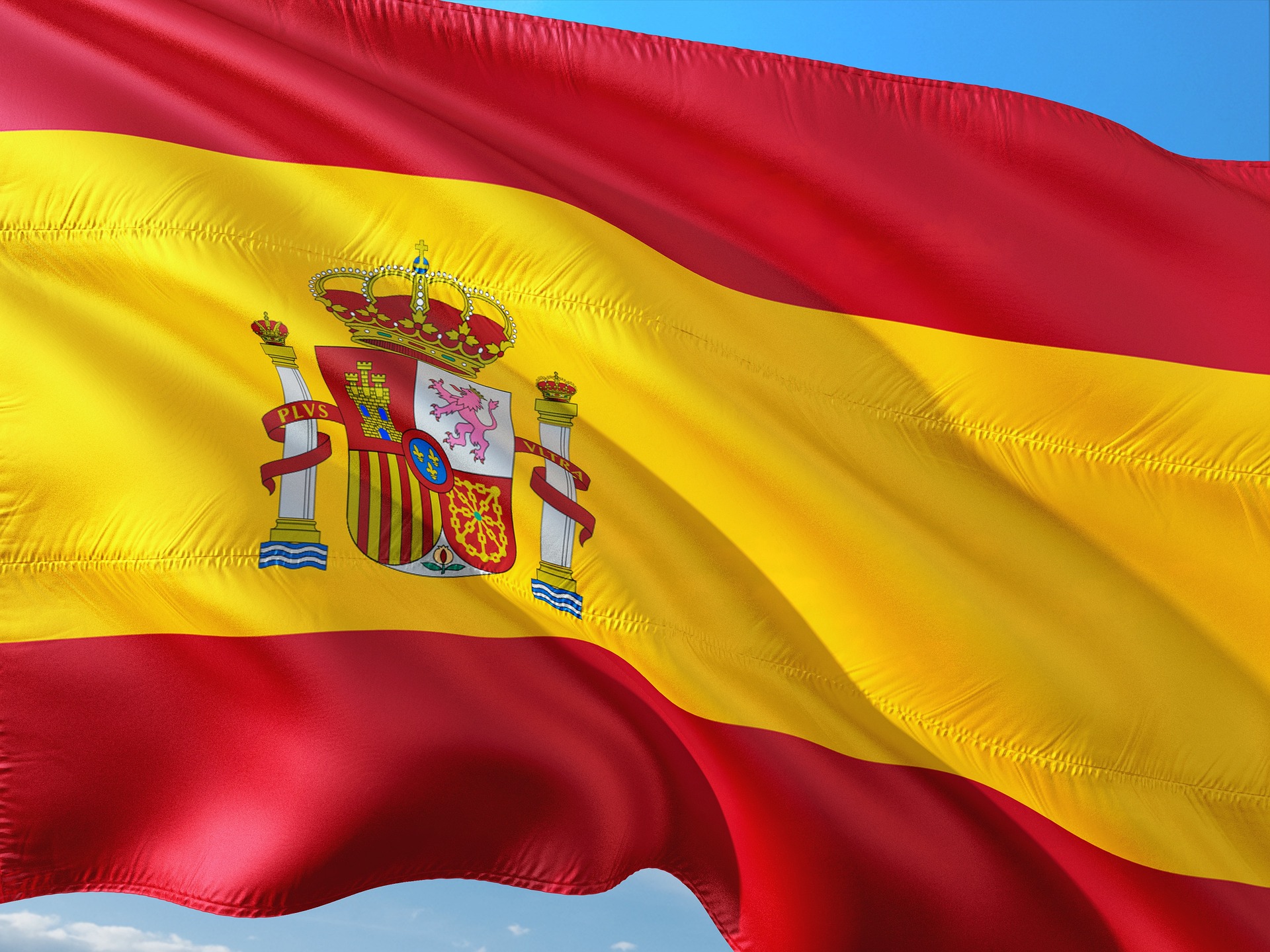 Flagge Spaniens – Wehende Landesfahne vor blauem Himmel, Spanien