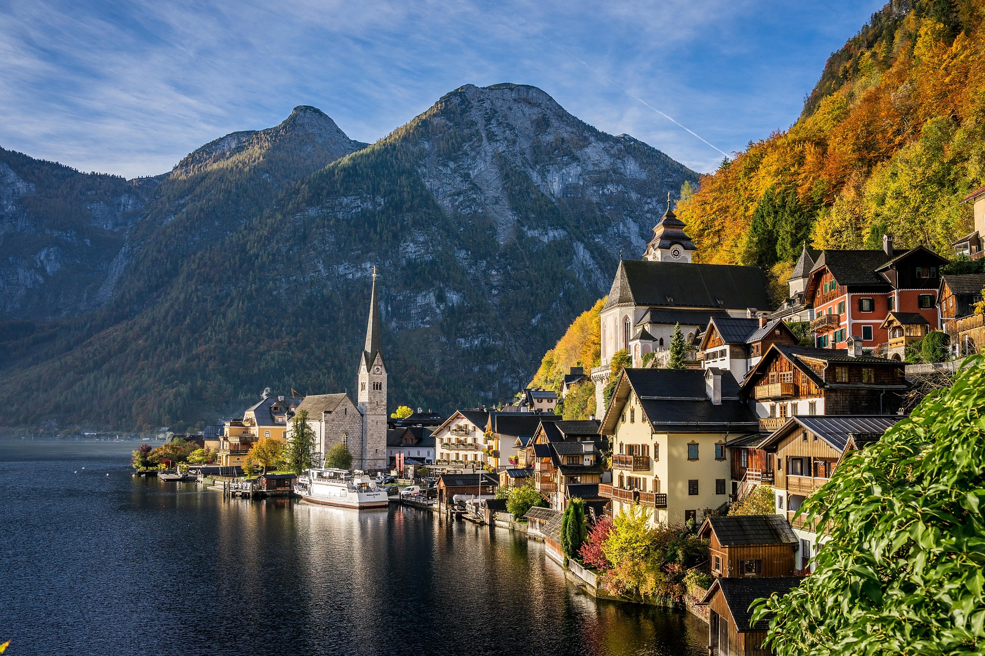 Österreichische Stadt in den Bergen – Häuser und Kirchturm vor Alpenpanorama, Österreich