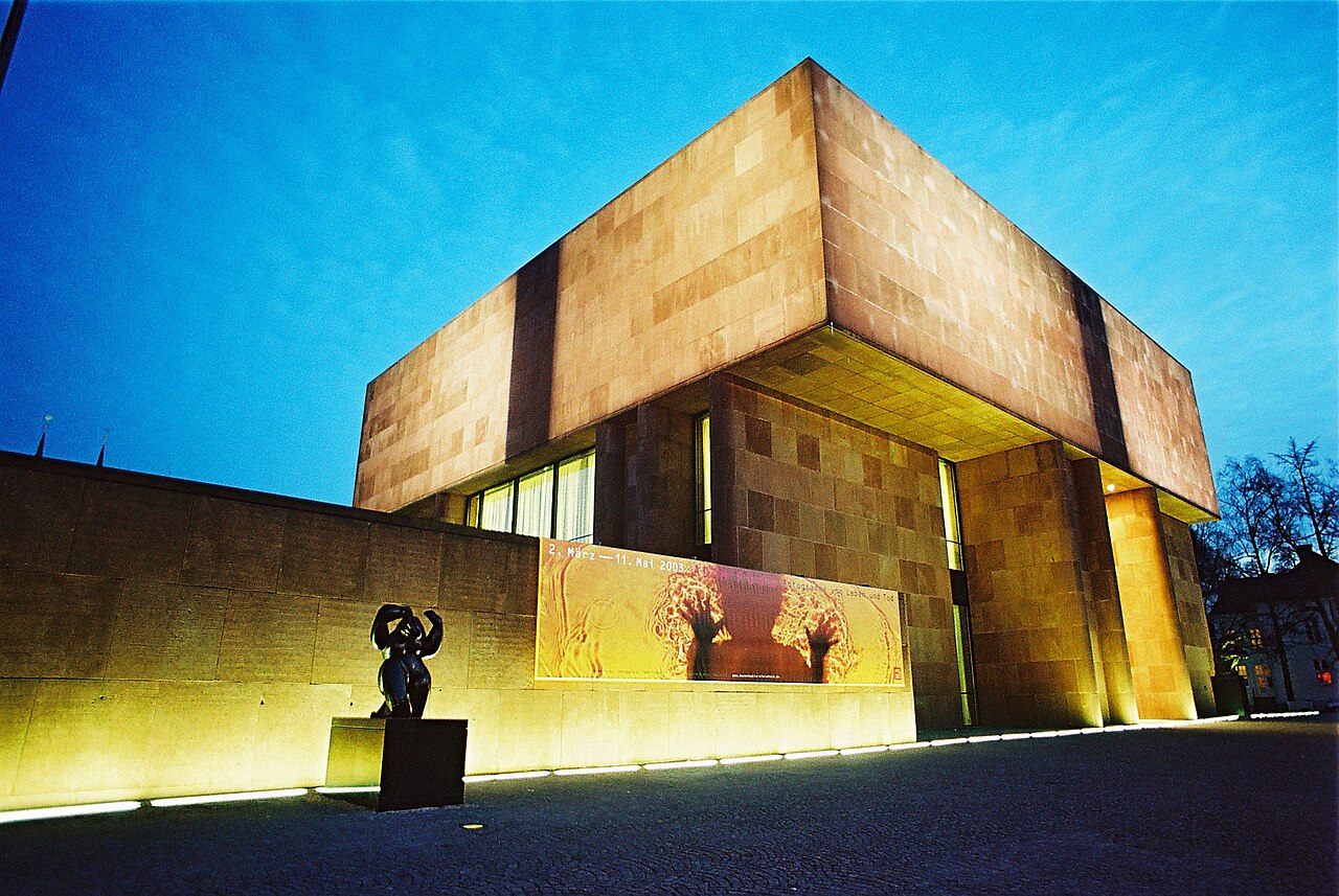 Kunsthalle Bielefeld bei Nacht – Beleuchteter roter Sandsteinwürfel von Philip Johnson im Skulpturenpark, Nordrhein-Westfalen