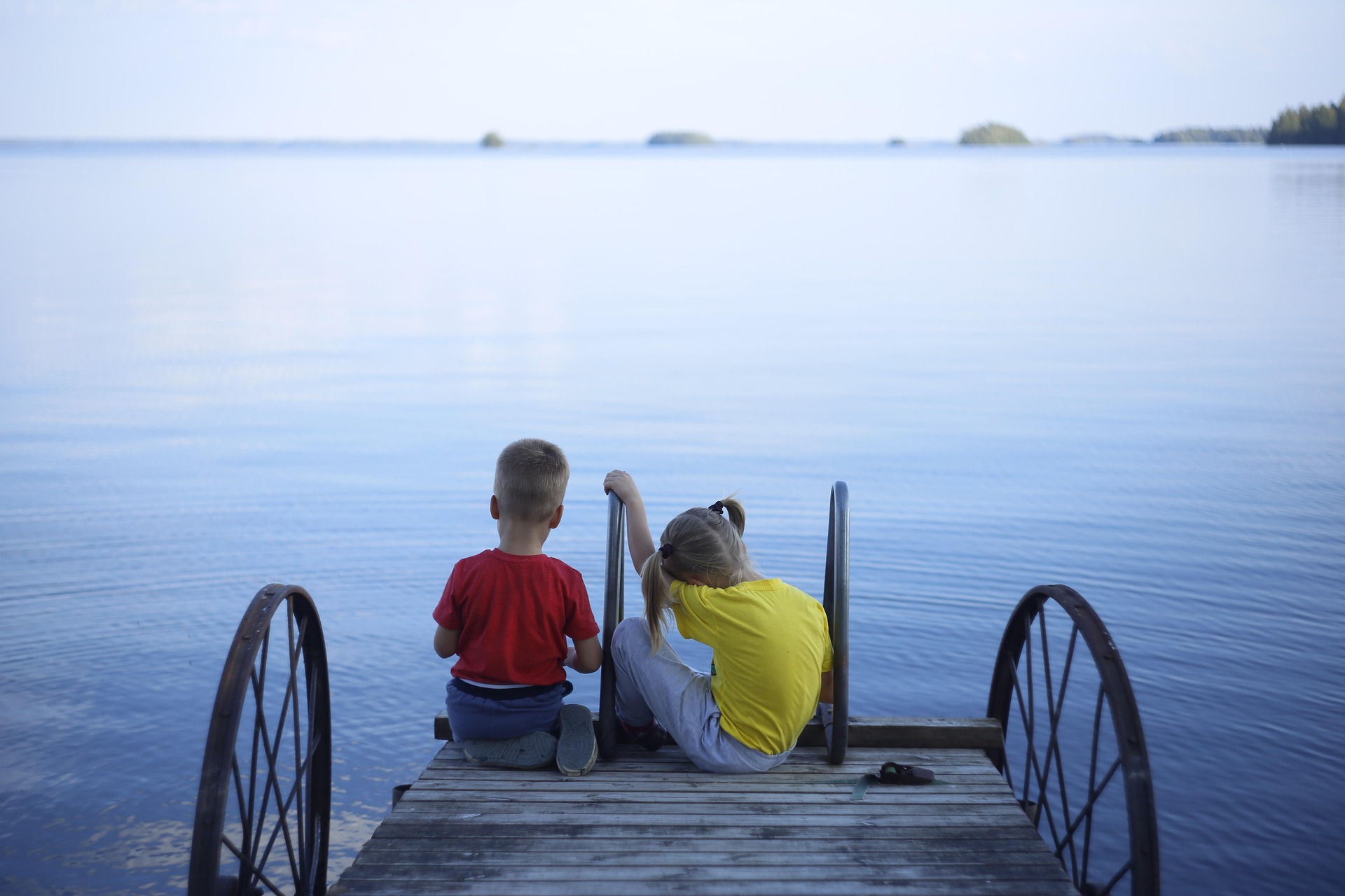 Kinder sitzen auf Brücke über See, Finnland