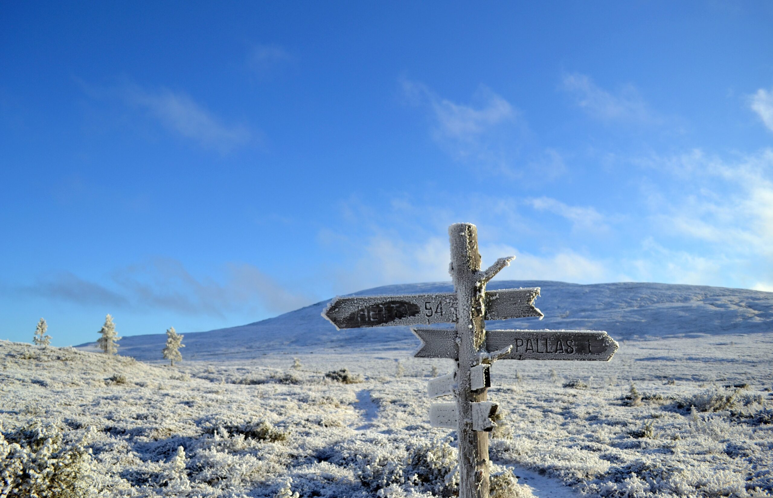 Lappland – Wegweiser im Schnee vor verschneiten Berggipfeln, Finnland
